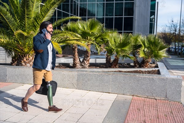 Businessman with prosthetic leg talking to the mobile while commuting along a financial district