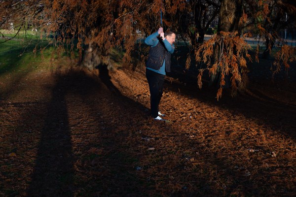 Male Golfer Below an Autumn Tree and Hitting His Golf Ball on Golf Course in Motion in a Sunny Day in Switzerland