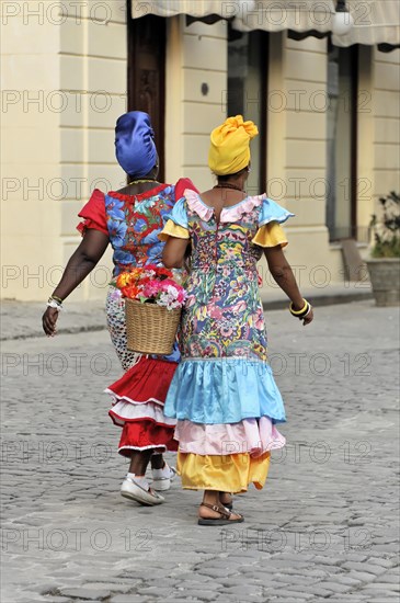 Two Creole women in colourful costumes walking in the centre of Havana, Cuba, Greater Antilles, Central America, America, Central America