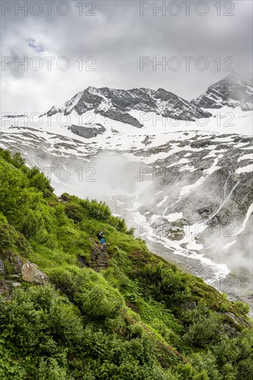 Mountaineers on a hiking trail, in the background glaciated peak Dosso Largo and glacier Schlegeiskees, cloudy atmospheric mountain landscape, ascent to Furtschaglhaus, Berliner Hoehenweg, Zillertal, Tyrol, Austria, Europe