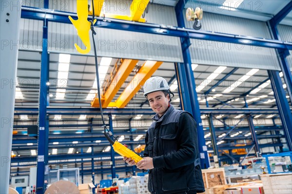 Worker with protective hard hat controlling an industrial crane with control remote