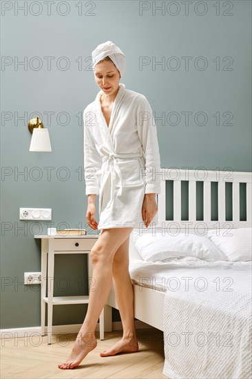 Young woman in bathrobe getting out of bed