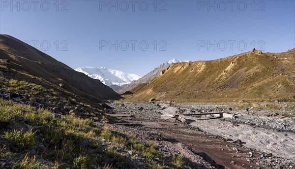 Bridge over the river Achik Tash, Achik Tash valley, behind glaciated and snow-covered mountain peak Pik Lenin, Trans Alay Mountains, Pamir Mountains, Osh Province, Kyrgyzstan, Asia