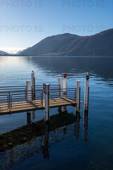 Jetty on Lake Lugano with Mountain and Sunlight Against Blue Clear Sky in Campione d'Italia, Lombardy, Italy, Europe