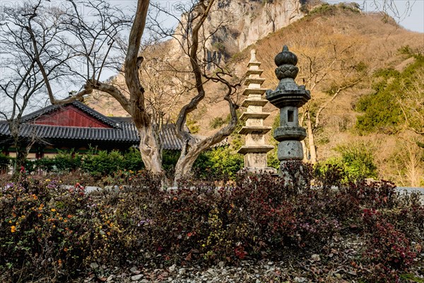 Stone carved lantern and nine story pagoda in Buddhist temple with mountain in background