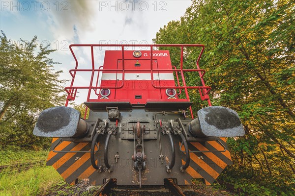 Rear view of a red locomotive on ballast tracks surrounded by trees, Lower Rhine, North Rhine-Westphalia, Germany, Europe