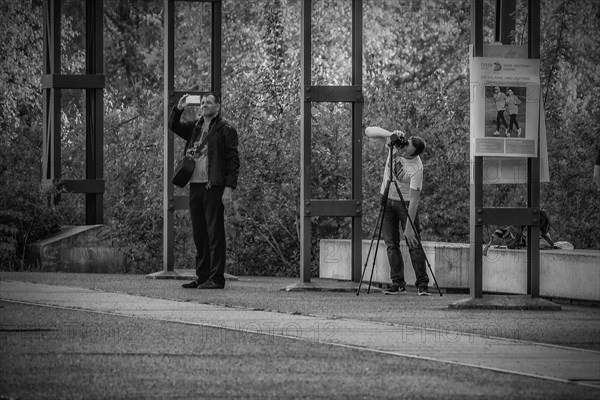 A man observes with large binoculars while a photographer stands next to him, Zeche Zollverein, Essen, North Rhine-Westphalia, Germany, Europe