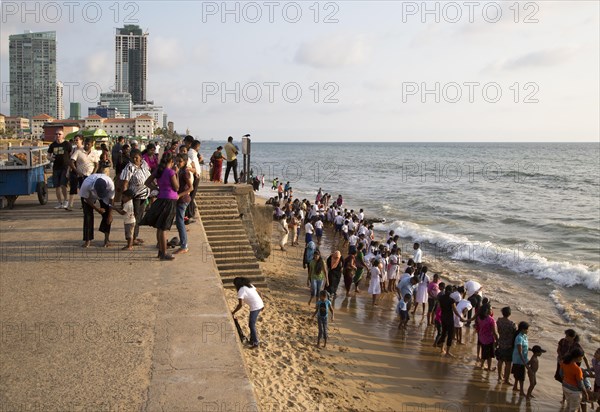 School children paddle in the sea on small sandy beach at Galle Face Green, Colombo, Sri Lanka, Asia