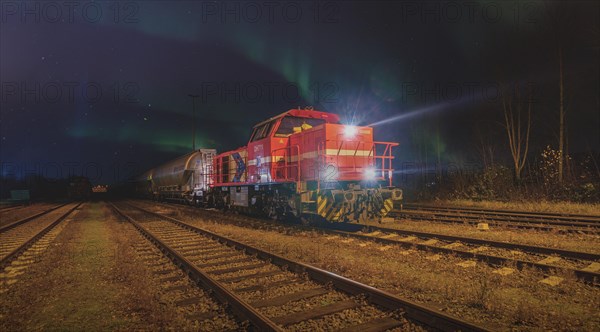 Red locomotive at night with northern lights in the background on an industrial track, Ruhr area, North Rhine-Westphalia, Germany, Europe