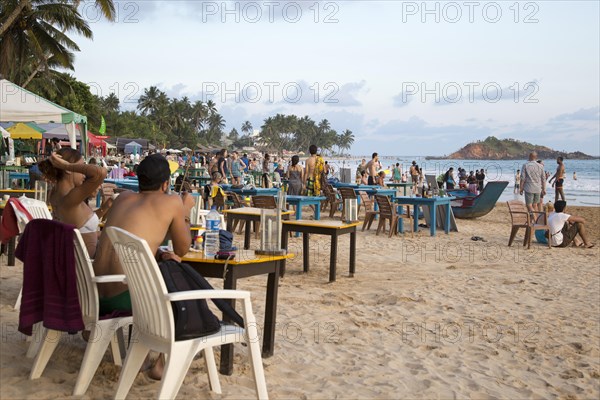 People sitting at tables of beach bar, Mirissa, Sri Lanka, Asia