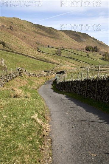 Narrow road and dry stonewall, Boredale valley, Martindale, Lake District national park, Cumbria, England, UK