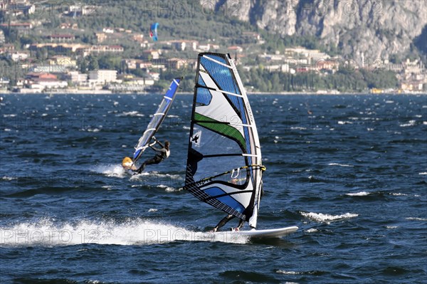 Windsurfers surfing in strong winds on Lake Garda near Malcesine, Veneto, Italy, Europe