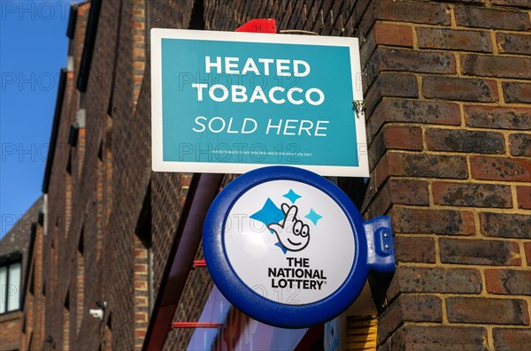 Wall signs advertising Heated Tobacco Sold here and the National Lottery, Reading, Berkshire, England, UK