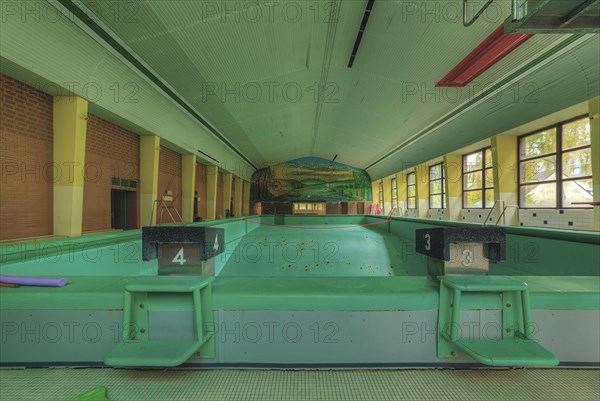 An abandoned indoor swimming pool with starting blocks and a mural in the background, Bad am Park, Lost Place, Essen, North Rhine-Westphalia, Germany, Europe