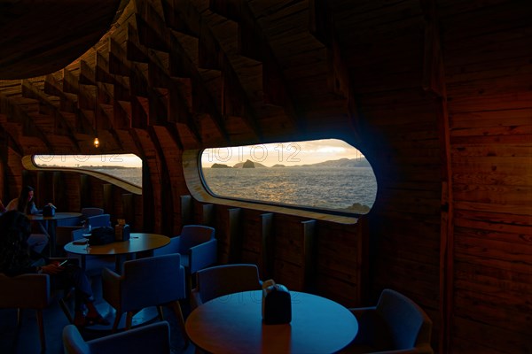 Cosy wooden interior of the Cella Bar with large windows overlooking the ocean at sunset, Madalena, Pico, Azores, Portugal, Europe