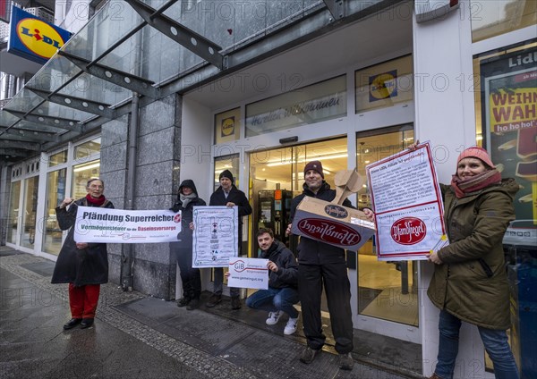 Germany, Berlin, 21.12.2023, action by Gemeingut in BuergerInnenhand (GiB), actions in front of branches of LIDL, Aldi and BMW, here a Lidl branch in Luisenstrasse / Berlin-Mitte, activists press a large deposit seal on a door of the LIDL branch, Carl Wassmuth, spokesman for Gemeingut: Super-rich like LIDL owner Dieter Schwarz only pay tiny tax rates, Europe