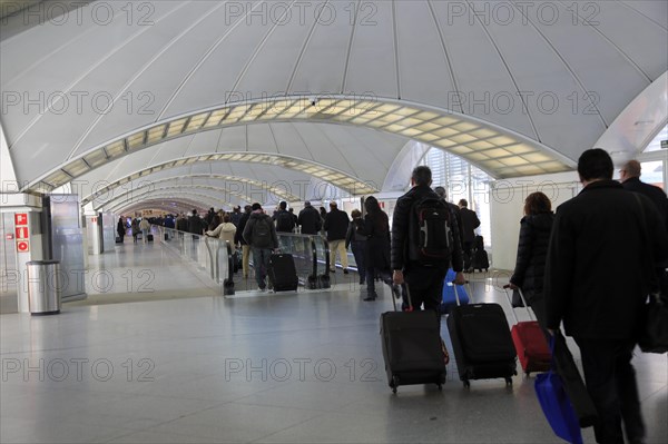 Passengers pulling luggage bags along a bright corridor, Atocha railway station, Madrid, Spain, Europe