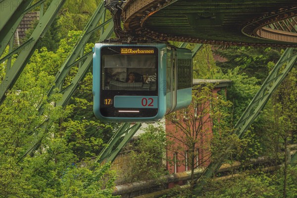 A suspension railway runs through an area of lush greenery and steel structures, suspension railway, Wuppertal, North Rhine-Westphalia, Germany, Europe