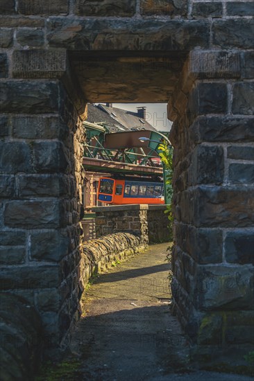 Suspension railway photographed through a stone arch, urban surroundings in the background, suspension railway, Wuppertal Sonnborn, North Rhine-Westphalia, Germany, Europe