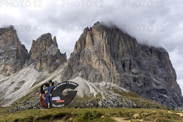 Traditional traditional costume couple advertising sign on the Sella Pass, behind Sassolungo, South Tyrol, Italy, Europe