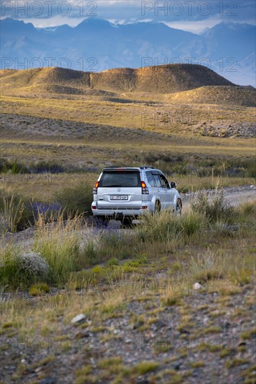An off-road vehicle drives on a gravel road, Kyrgyzstan, Asia