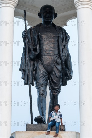 Child at the foot of a Mahatma Gandhi monument, statue, former French colony of Pondicherry or Puducherry, Tamil Nadu, India, Asia