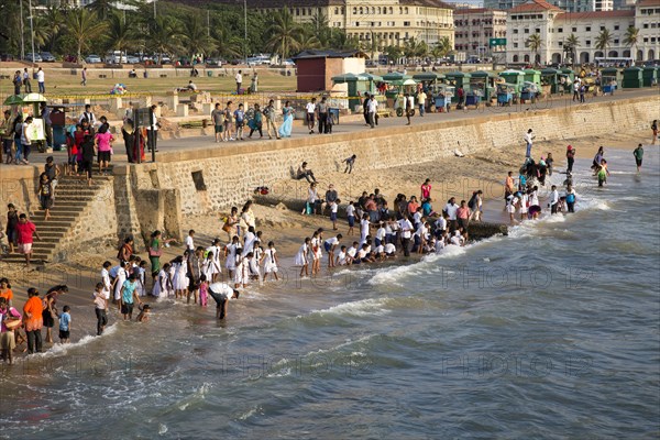 School children paddle in the sea on small sandy beach at Galle Face Green, Colombo, Sri Lanka, Asia