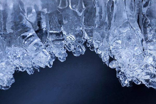 Ice formations and icicles formed by frost and freezing cold temperatures over running water of stream