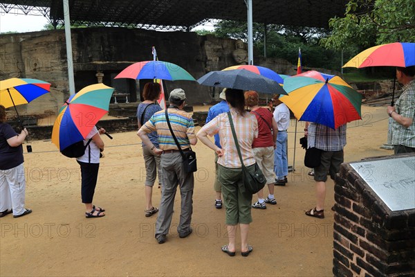 Tourists carrying umbrellas Gal Viharaya, UNESCO World Heritage Site, the ancient city of Polonnaruwa, Sri Lanka, Asia
