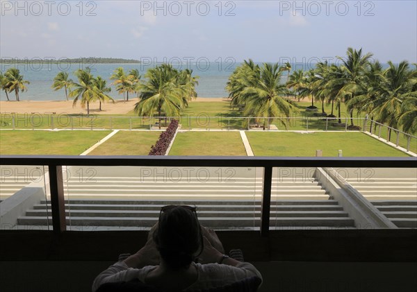 Woman relaxing on hotel balcony, Amaya Beach Resort hotel, Pasikudah bay, Eastern Province, Sri Lanka, Asia