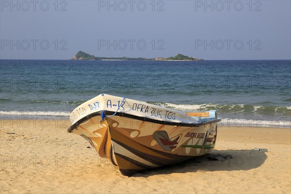 Boat on tropical beach at Nilavelli, Trincomalee, Sri Lanka, Asia with Pigeon Island in background, Asia
