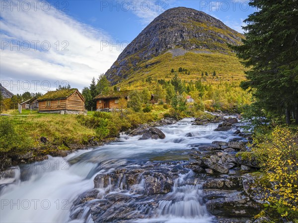 Autumn in Valldalen, cabins by a river in front of a mountain, Reinheimen National Park, More og Romsdal, Norway, Europe