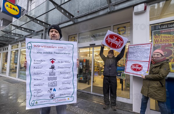 Germany, Berlin, 21.12.2023, action by Gemeingut in BuergerInnenhand (GiB), actions in front of branches of LIDL, Aldi and BMW, here a Lidl branch in Luisenstrasse / Berlin-Mitte, activists press a large deposit seal on a door of the LIDL branch, Carl Wassmuth, spokesman for Gemeingut: Super-rich like LIDL owner Dieter Schwarz only pay tiny tax rates, Europe