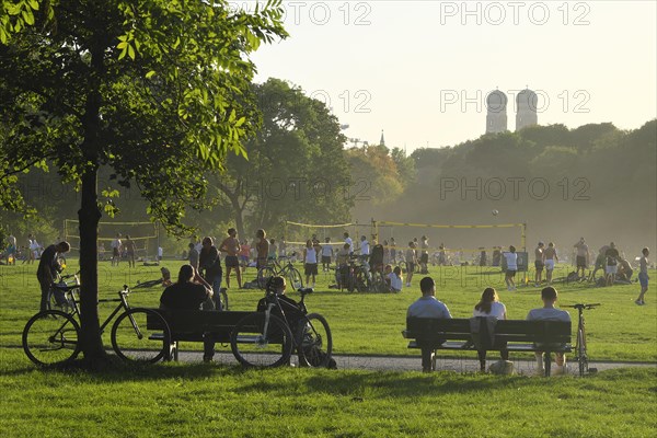 People enjoying the autumn sun on two benches in the English Garden, Munich, Bavaria, Germany, Europe