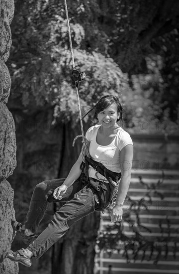 A woman climbing a rock face, secured with a rope and harness, Hohenzollern Bridge, Cologne Deutz, North Rhine-Westphalia, Germany, Europe