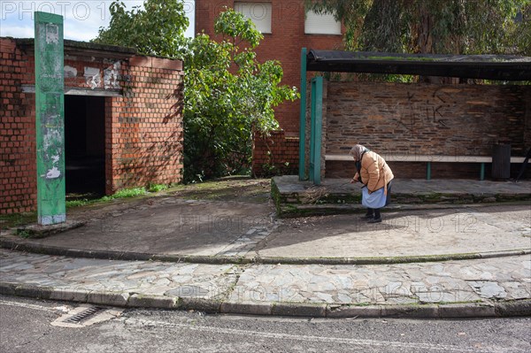 Old woman sweeping the street at a bus stop, Riomal de Abajo, Extremadura, Spain, Europe