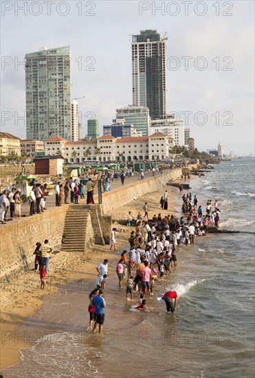 School children paddle in the sea on small sandy beach at Galle Face Green, Colombo, Sri Lanka, Asia