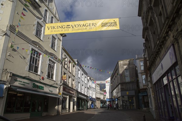 Threatening grey rain clouds over town centre street, Falmouth, Cornwall, England Viking Voyagers advertising banner