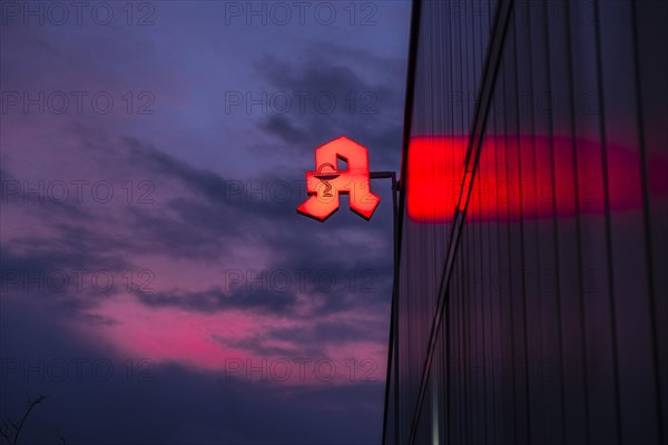 Illuminated pharmacy sign in front of a stormy sky on a facade in Duesseldorf, Germany, Europe