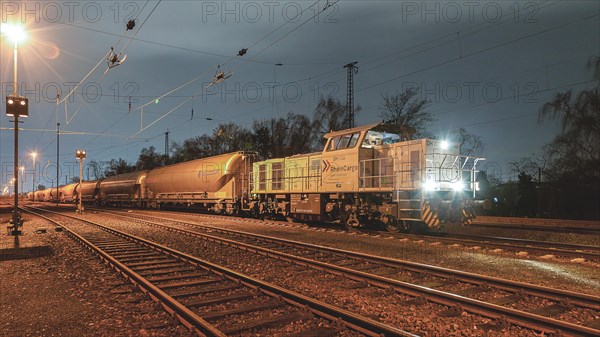 At night at the station, a grey diesel locomotive stands on the tracks next to freight wagons, Ruhr area, North Rhine-Westphalia, Germany, Europe