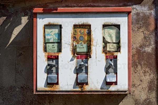 Old rusty triple chewing gum machine on a wall, vending machine for children for chewing gum and small toys with surprise, Germany, Europe