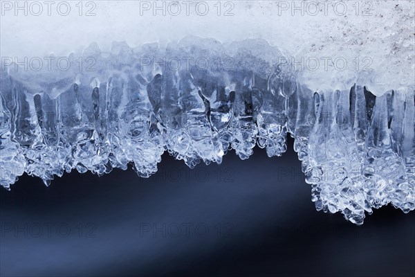 Ice formations and icicles formed by frost and freezing cold temperatures over running water of stream