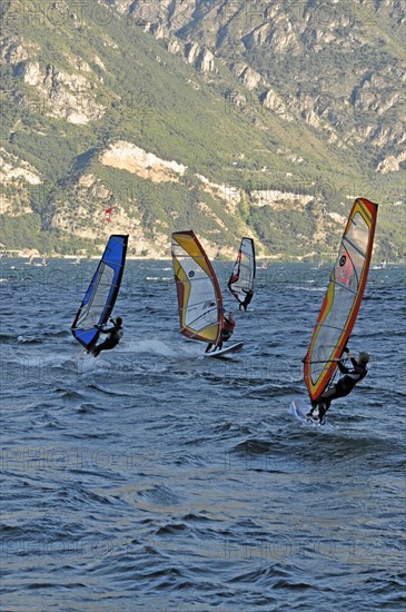 Windsurfers surfing in strong winds on Lake Garda near Malcesine, Veneto, Italy, Europe