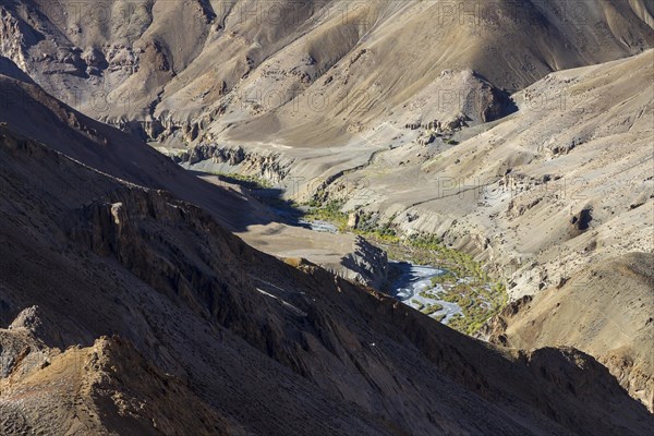 Niri Chu valley of Zanskar, with some vegetation at its bottom and rugged slopes above, photographed on a sunny September day from the Nyalo Kuntse pass. Zanskar Range of the Himalayas, the dry, desert mountains belonging to the Thetys Himalayas. Kargil District, Union Territory of Ladakh, India, Asia