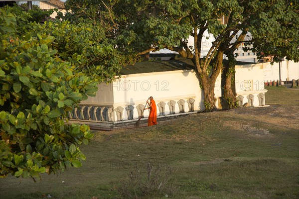 Buddhist monk sweeping temple grounds in the historic town of Galle, Sri Lanka, Asia