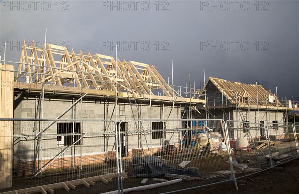 New houses under construction in the village of Bawdsey, Suffolk, England, UK dark storm clouds overhead