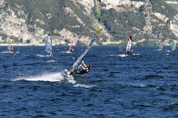 Windsurfers surfing in strong winds on Lake Garda near Malcesine, Veneto, Italy, Europe