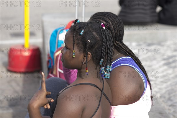 Two young black woman with twisted pigtails in Piazza de Ferrari, Genoa, Italy, Europe