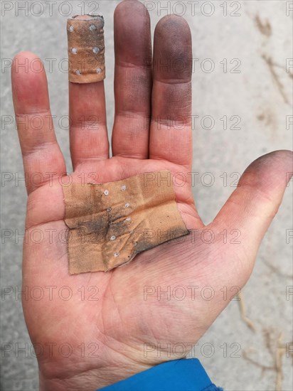 Close up of a dirty hand of a man, with protection plasters of a industry worker after finishing work