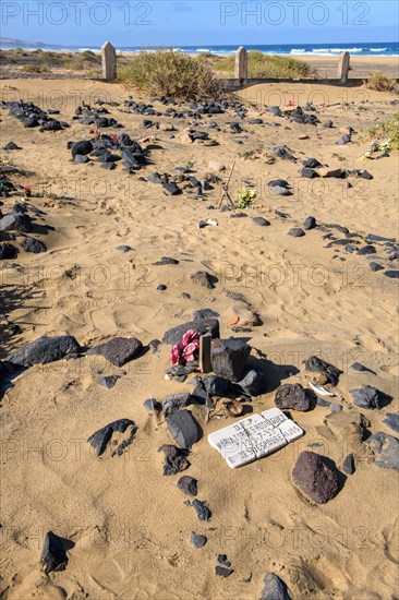 View of old sandy historical cemetery from 1950s in the foreground flower decorated grave with tombstone of Maria Torres Rodriguez died 1953, behind several graves marked by stones of abandoned village Cofete on west coast of peninsula Jandia, in the background Atlantic Ocean, Cofete, Jandia, Fuerteventura, Canary Islands, Canary Islands, Spain, Europe